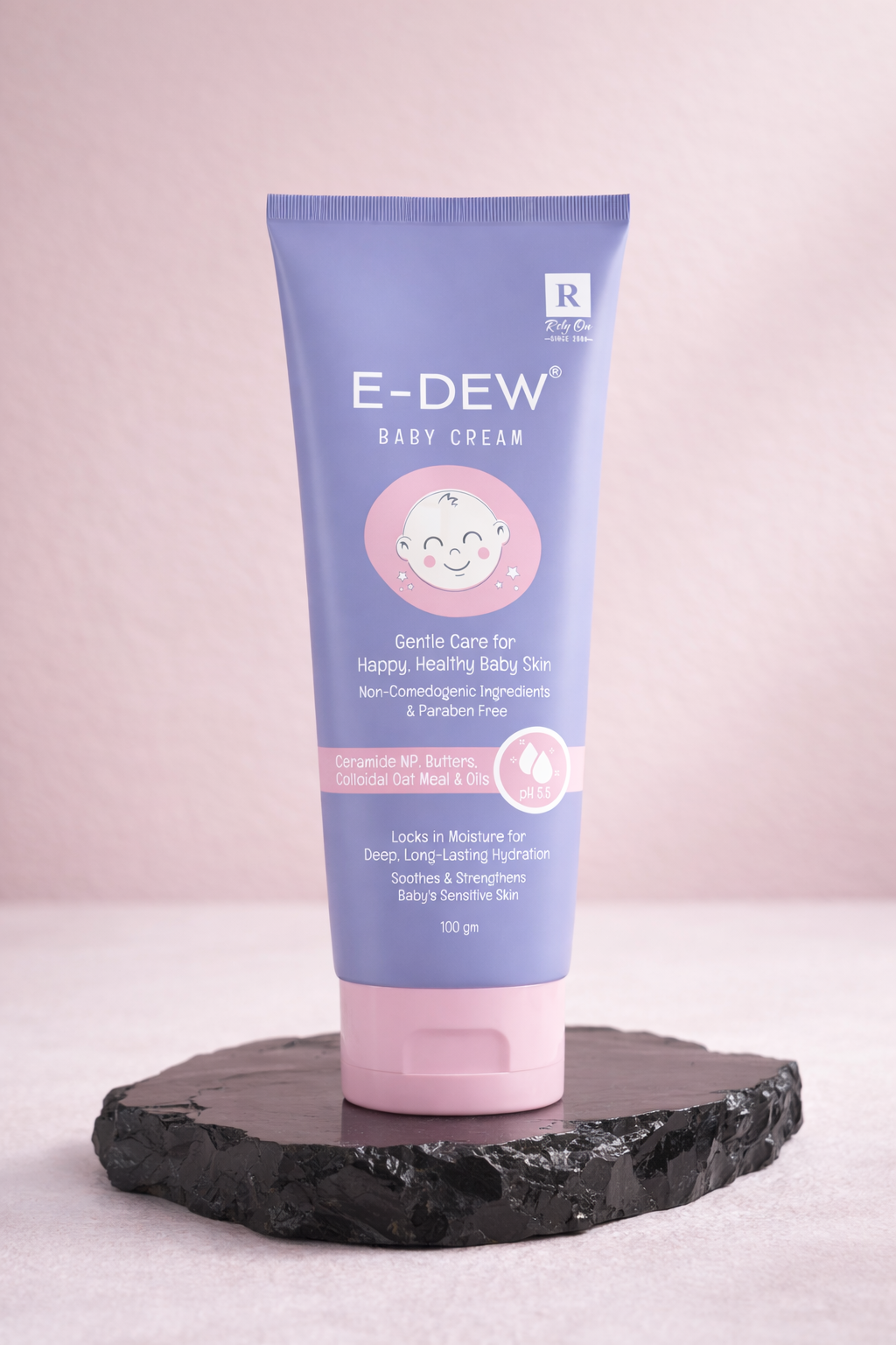 E-Dew baby cream tube on a dark stand with a pink background